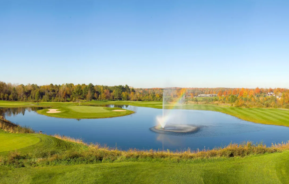 an overview of the greens at Hawk Ridge Course, with a large pond in the centre and a fountain shooting water out of the pond