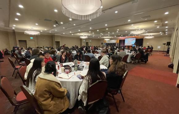a wide angle view of a conference room filled with Indigenous students at a prior event