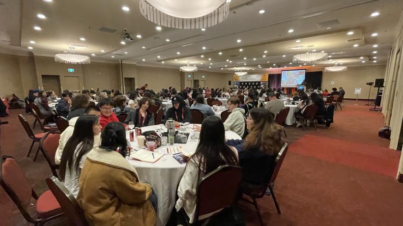 a wide angle view of a conference room filled with Indigenous students at a prior event